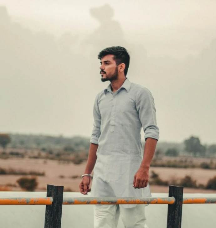 man in white button up shirt standing beside brown wooden fence during daytime